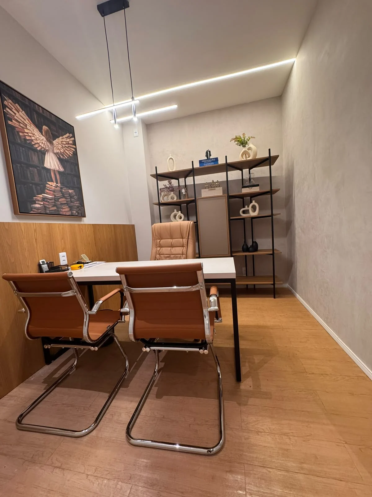 Consultório terapêutico 1 da Sallus em Lauro de Freitas, com mesa, cadeiras, estante decorada e quadro